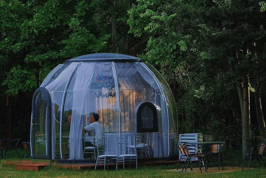 Spacious transparent dome house interior with bed and furniture
